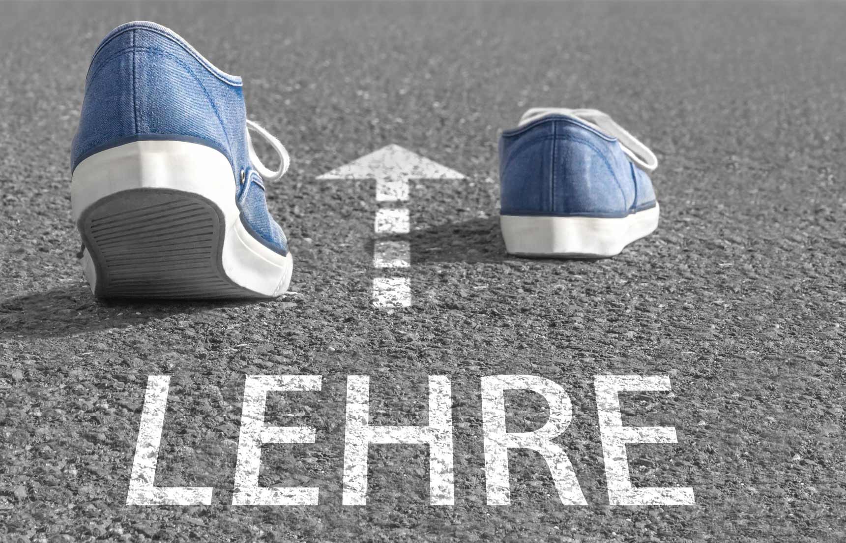 Schuhe auf Asphaltweg mit Pfeil